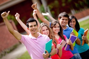 Happy group of students with arms up outdoors